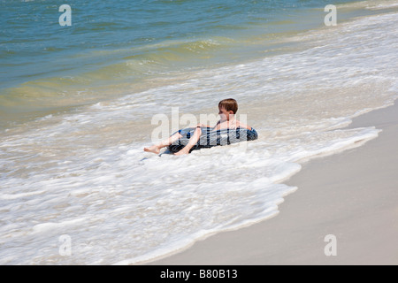 Boy flotte dans la chambre à air dans le golfe du Mexique surf au parc d'état de la péninsule de St Joseph à Port St Joe en Floride Banque D'Images