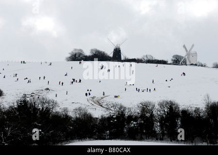 La colline de point les chiffres comme une peinture Lowry comme ils profiter de la neige à la Jack et Jill windmills dans Clayton Sussex UK Banque D'Images