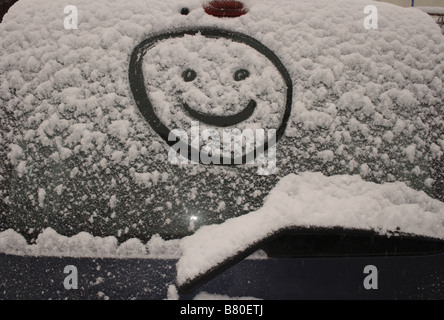 Smiley dessiné dans la neige sur le pare-brise arrière d'une voiture. Photo par Willy Matheisl Banque D'Images