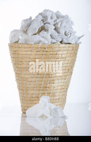 Corbeille à papier en osier bin plein de tissus utilisés avec un seul tissu utilisé se trouvant en face de bin Banque D'Images