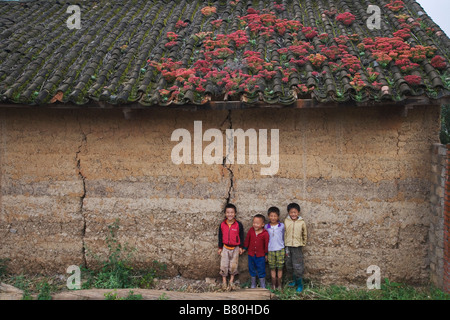 Les enfants et maison de village avec toit en tuiles colorées couvertes par la province du Yunnan Chine moss Banque D'Images