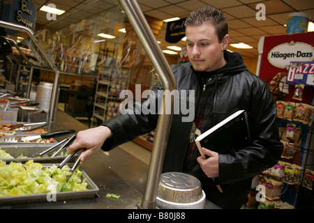 Jeune homme à un bar à salades. Banque D'Images