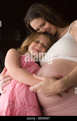 Pregnant mother hugging her daughter et holding hand Banque D'Images