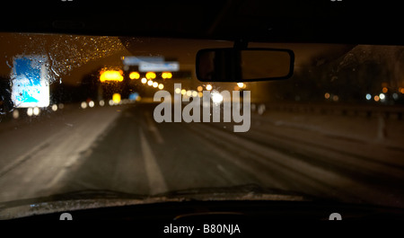 Location de voiture sur l'autoroute déserte la nuit vide des panneaux d'avertissement dans la neige Banque D'Images