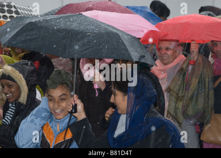 Les femmes portent des parapluies Sikh comme la pluie se déverse vers le bas sur le Vaisakhi procession à Woolwich, Londres Banque D'Images