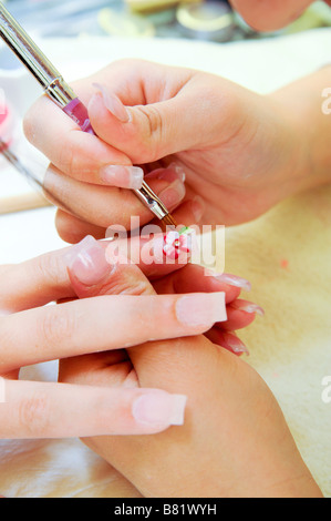 La décoration de faux ongles avec une brosse dans un salon de manucure Banque D'Images