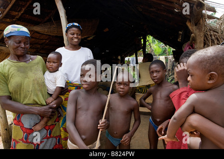 Une famille sont heureux de poser pour une photo en face de leur maison dans une partie reculée de la jungle du PEE au Nigeria Banque D'Images