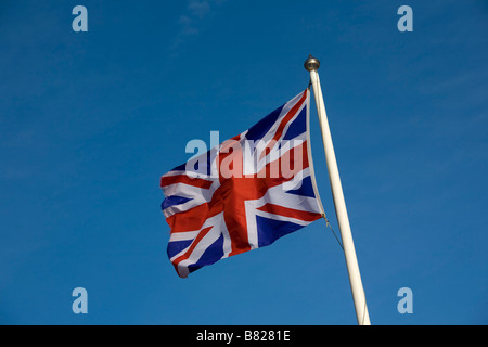 Union Jack flag flying sur mât contre le ciel bleu Banque D'Images