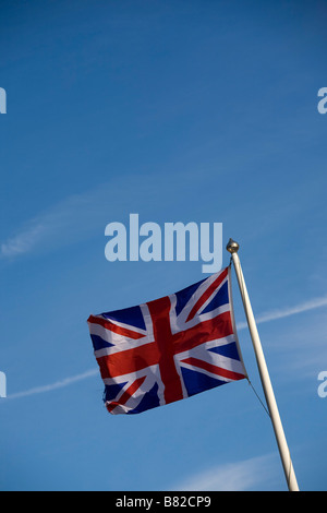 Union Jack flag flying sur mât contre le ciel bleu Banque D'Images