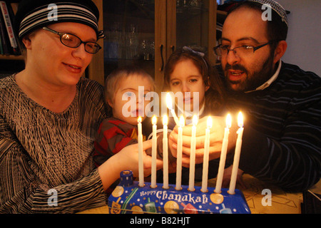 Une famille de quatre personnes célébrer la fête juive de Hanoucca comme Chanucah / ils allument un menorah avec des bougies. Banque D'Images