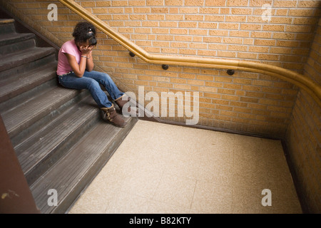 Teenage african american girl de pleurer sur l'escalier à l'école, assis sur l'étape Banque D'Images