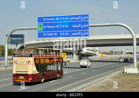 Visite touristique de Dubaï à impériale à toit ouvert, Big bus Compagnie conduisant le long de l'autoroute, panneau bleu de destination Emirats Arabes Unis Moyen-Orient Banque D'Images