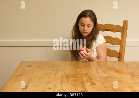 Jeune femme assise à la table à la recherche d'apple Banque D'Images