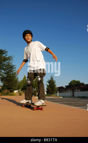 Boy riding skateboard dans un soleil d'après-midi Banque D'Images