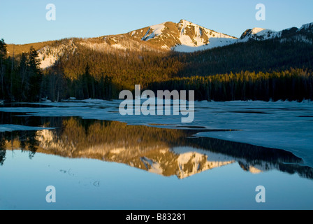 Belle réflexion d'une montagne pendant le coucher du soleil dans l'eau immobile d'un lac gelé en partie Banque D'Images