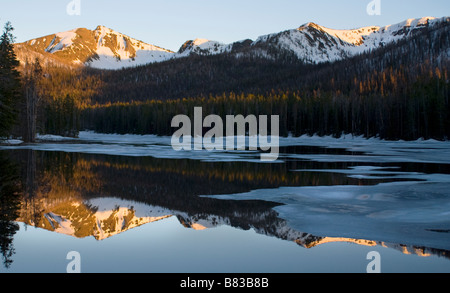 Belle réflexion d'une montagne pendant le coucher du soleil dans l'eau immobile d'un lac gelé en partie Banque D'Images