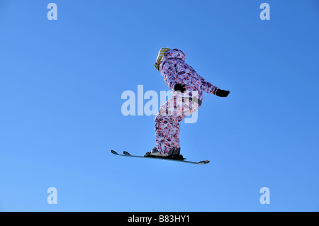 Une fille dans des vêtements colorés sur les skis de saut Banque D'Images