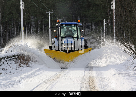 Un tracteur agricole avec charrue attaché clearing routes rurales dans l'Aberdeenshire, Scotland, UK, de la neige en hiver Banque D'Images