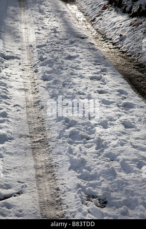 Car les traces de pneus dans la neige sur un bois lane, Surrey, Angleterre. Banque D'Images