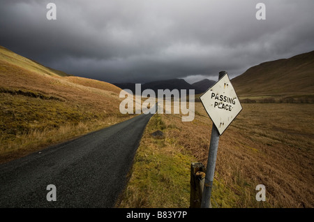 Lonely seule piste route de montagne dans la région de Highlands avec passant signe avec trous de balle. Banque D'Images