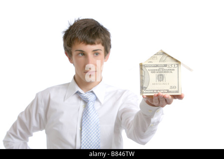 Business man holding une maison faite de l'argent dans le studio Banque D'Images