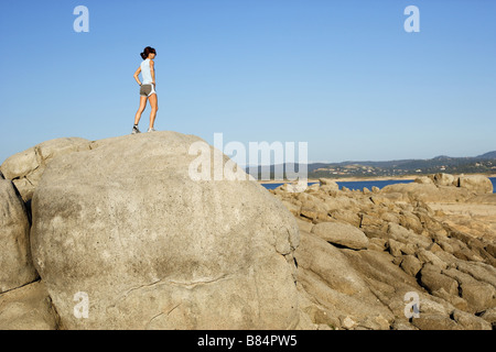 Une femme sur un jog climes au sommet d'un rocher et saute de joie Banque D'Images