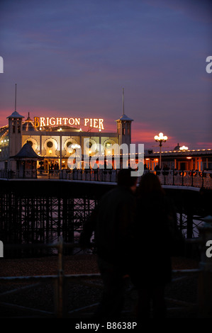 Un couple se tenir debout avec leurs bras autour de l'autre en face de la jetée de Brighton dans la nuit. Photo Jim Holden. Banque D'Images