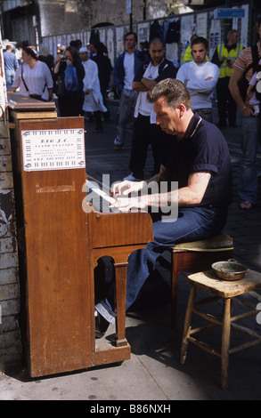 Big J.C. divertit les clients avec son jeu de piano en plein air dans la région de Brick Lane, East London. Banque D'Images