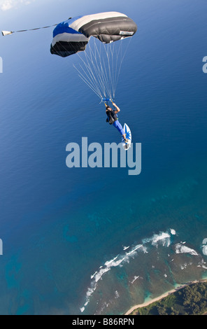 Parachutiste sous l'auvent est volant le long de la ligne de coût à partir d'Hawaï se prépare à faire un atterrissage avec une plage de surf. Banque D'Images