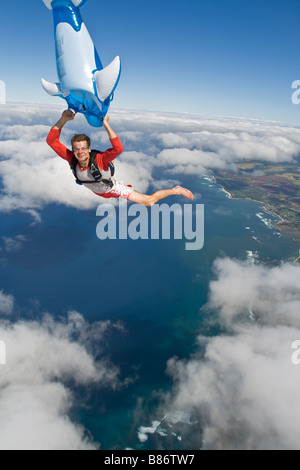 Parachutiste saute sur Hawaï avec un air gonflable jouet dans ses bras. Le plongeur a beaucoup de temps à jouer avec le jouet. Banque D'Images