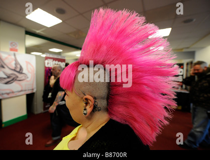 Jeune femme avec une coupe de cheveux rose vif style mohican à la Convention de Brighton Tattoo Banque D'Images