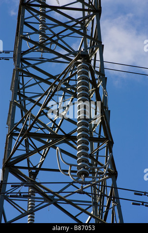 Close up d'isolateurs en céramique entre les câbles d'alimentation électrique haute tension pylône Banque D'Images