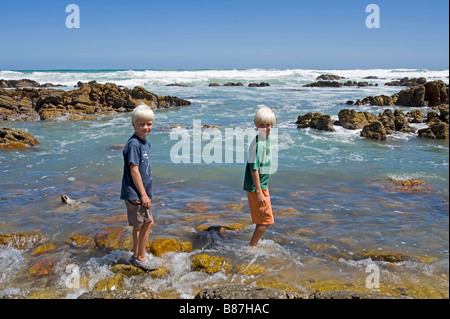 Deux garçons debout à l'extrémité sud du continent africain les roches à Cap des aiguilles en Afrique du Sud Banque D'Images