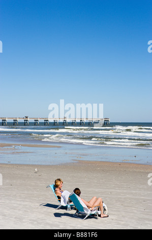 Deux femmes en train de bronzer sur des chaises en face de la jetée, Jacksonville Beach, Florida, USA Banque D'Images