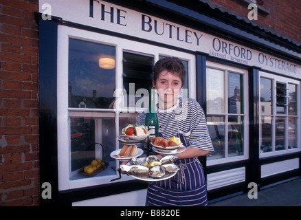 Une serveuse affiche une sélection de fruits de mer locaux à l'extérieur de la façade de l'Orford. Oysterage Butley Suffolk Orford England UK Banque D'Images