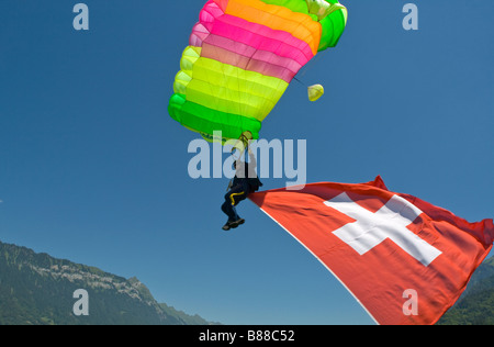 Parachutiste sous voilure va atterrir avec un grand drapeau suisse derrière lui.Avec cette démo jump le plongeur est représente le sport. Banque D'Images