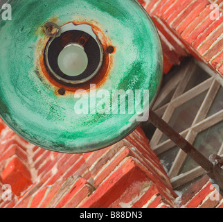 Vieille lampe n'est pas oxydée, à partir de laquelle l'intérieur du cuivre est devenu vert, suspendu à un mur de brique rouge Banque D'Images