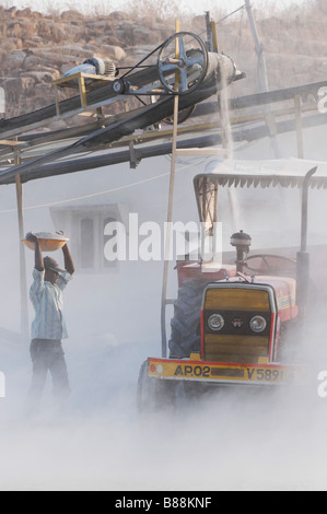 L'homme indien de mettre de la pierre concassée dans une remorque, entouré par la poussière, non protégé, à une roche travaille en Inde Banque D'Images