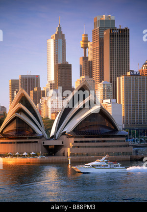 Taxi jet boat traversant le Port de Sydney en vertu de l'Opera House et sur les toits de la ville à l'aube Banque D'Images