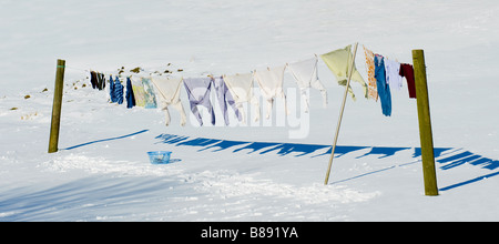 Lavage accroché (piquets), se déplaçant dans le vent, ombres projetées sur un sol blanc couvert de neige (scène de neige de jardin d'hiver graphique) - West Yorkshire, Angleterre Royaume-Uni. Banque D'Images