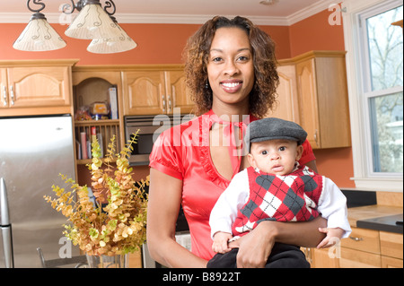 African American Woman pose avec son bébé dans la cuisine moderne entièrement rénové Banque D'Images