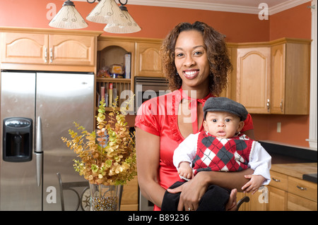 African American Woman pose avec son bébé dans la cuisine moderne entièrement rénové Banque D'Images