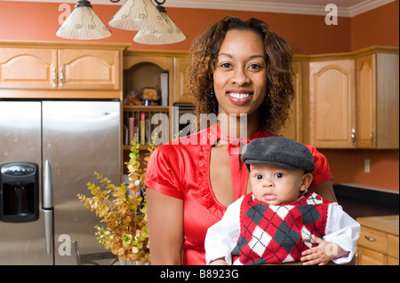 African American Woman pose avec son bébé dans la cuisine moderne entièrement rénové Banque D'Images