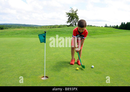 Un garçonnet de cinq ans jouant au golf sur un green d'un terrain de golf Banque D'Images