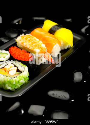 Assortiment de sushi sur plaque de cailloux noirs sur fond noir Banque D'Images