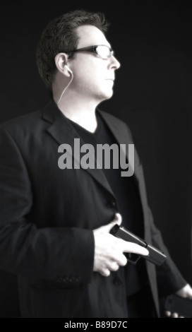 Portrait d'un homme portant des lunettes de soleil et la tenue d'un téléphone mobile et l'arme à feu. À l'aide d'une oreillette. Banque D'Images