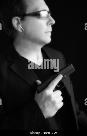 Portrait d'un homme portant des lunettes de soleil et tenant un pistolet. (Soft focus glow effect) Banque D'Images