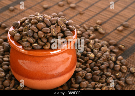 Les grains de café torréfié moyen à partir de la région de Nyeri, Kenya dans un bol en terre cuite se répercutent aussi sur un tapis de gazon brun Banque D'Images