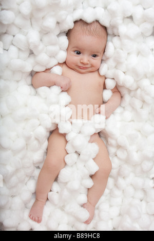 Adorable petite fille de 2 mois s'étendant dans un lit de coton blanc Banque D'Images