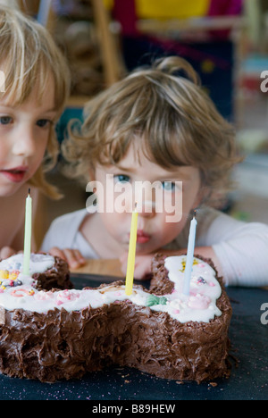 Un jeune garçon souffle les bougies sur son gâteau d'anniversaire Banque D'Images